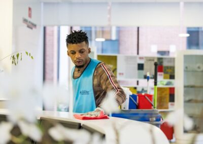 Un comptoir d'accueil nettoyé par un agent en blouse Candor Propreté